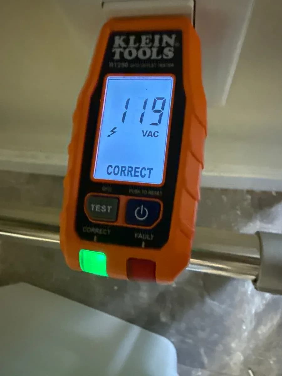 Close-up of an electrical receptacle tester displaying 119 VAC and a correct wiring indication.