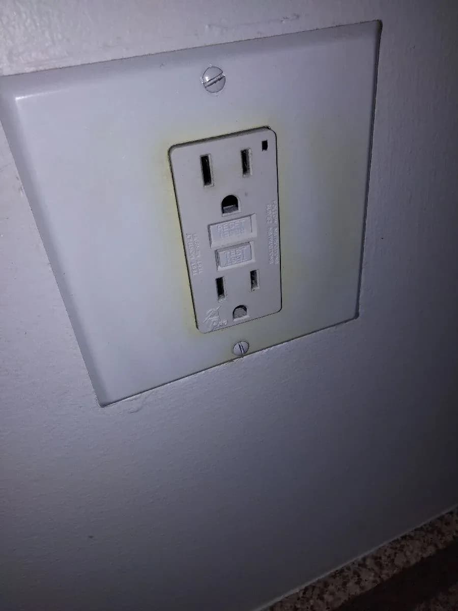 Close-up of a white GFCI electrical receptacle installed in a wall with a matching cover plate.