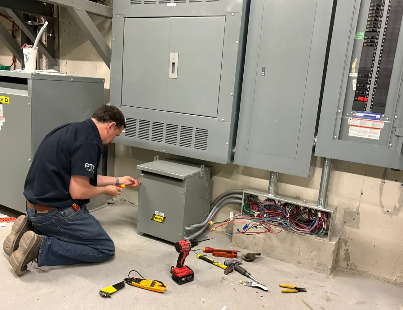 PTX electrician working on commercial electrical distribution equipment