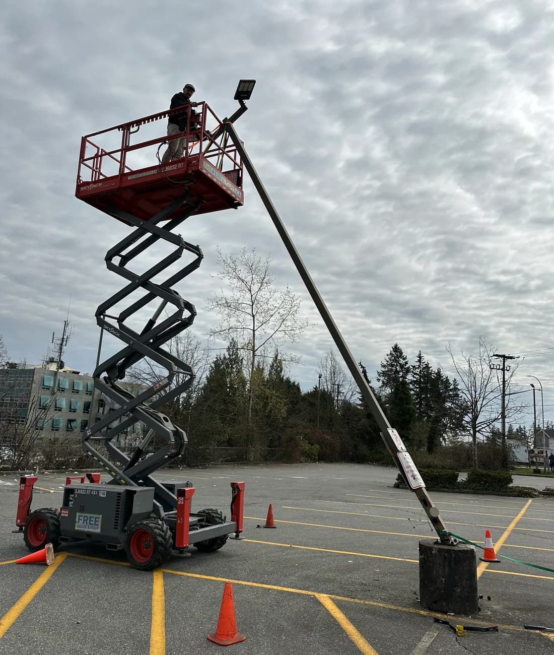 Electrician using a lift to service parking-lot lighting