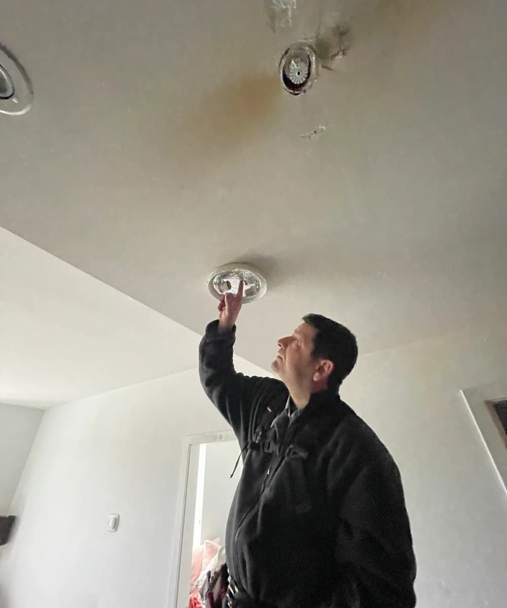 Electrician replacing a ceiling-mounted smoke detector