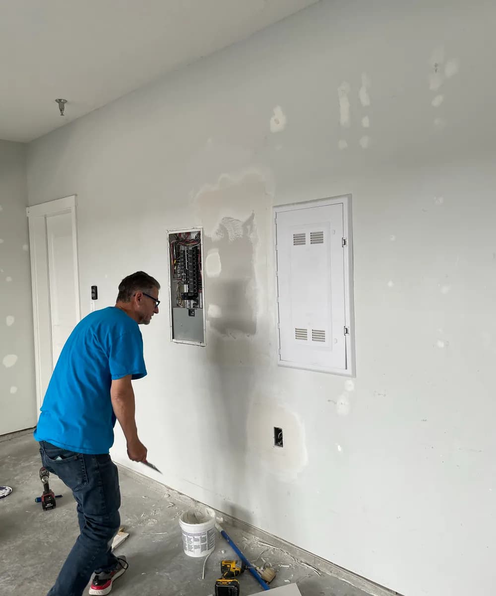 PTX team member completing drywall repair after electrical access work