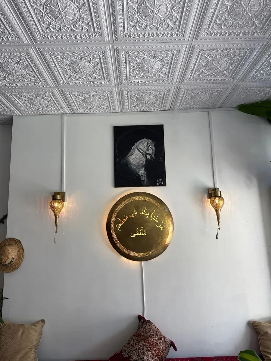 Interior wall with two illuminated decorative wall sconces and a larger illuminated circular wall feature beneath a patterned ceiling.
