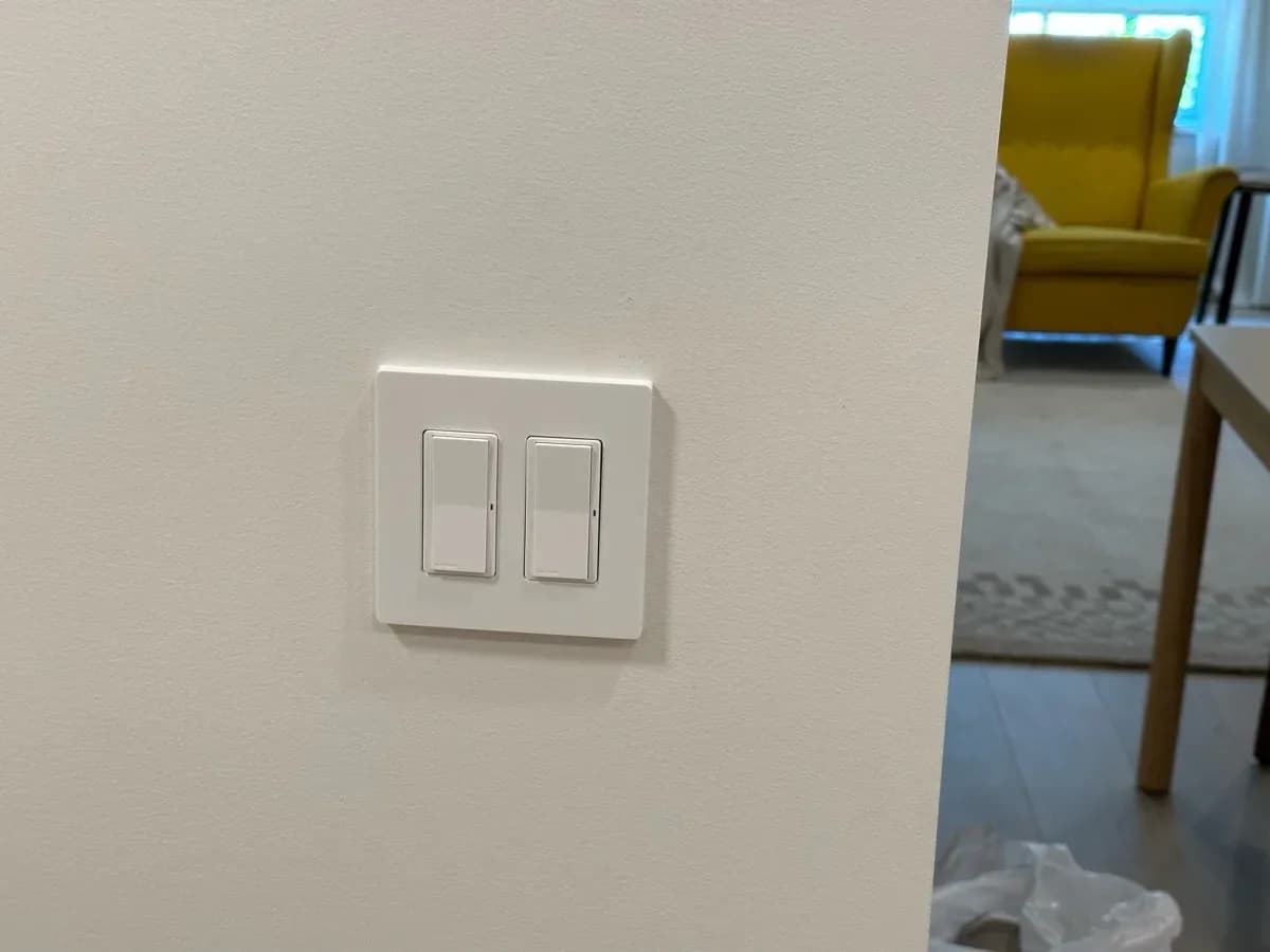 White wall-mounted plate with two rocker light switches installed on a finished interior wall.
