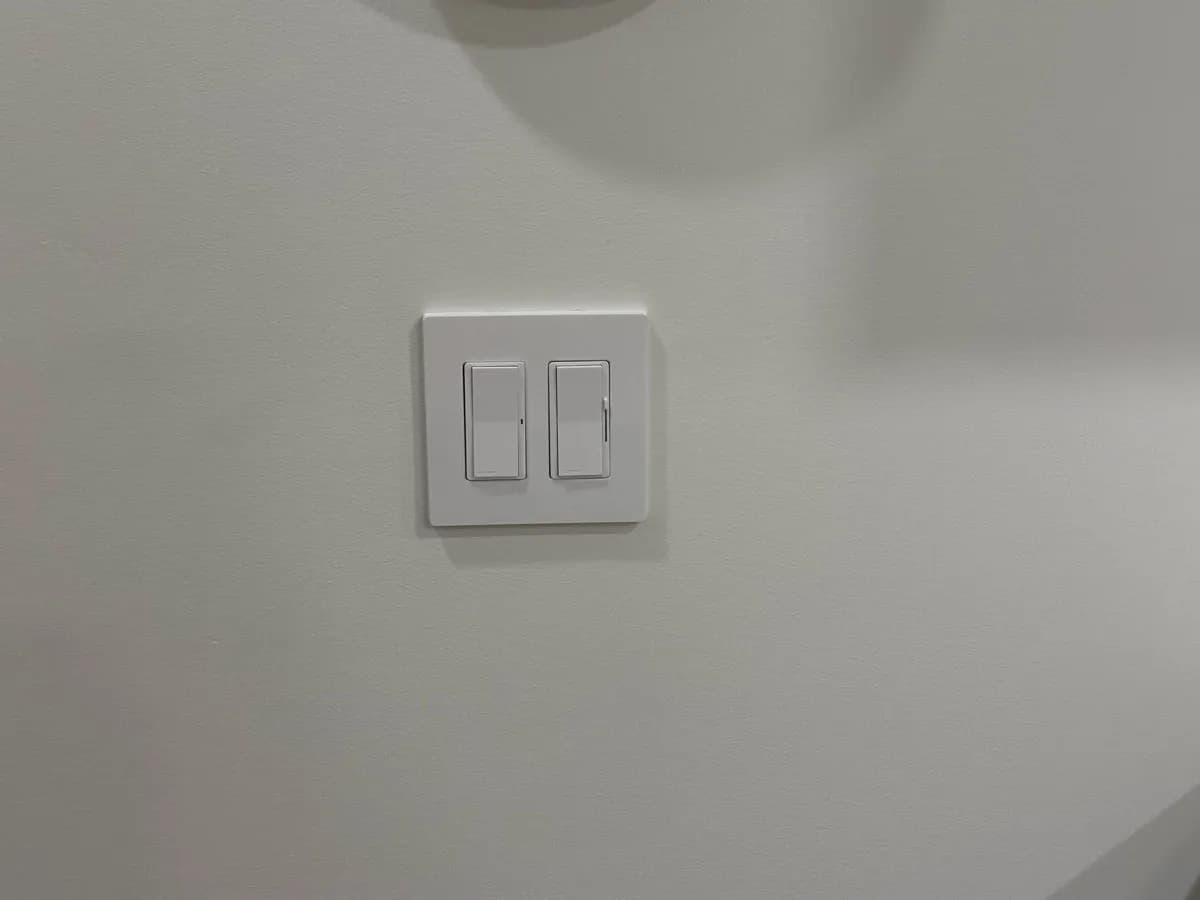 White two-switch wall plate installed on a light-colored wall.