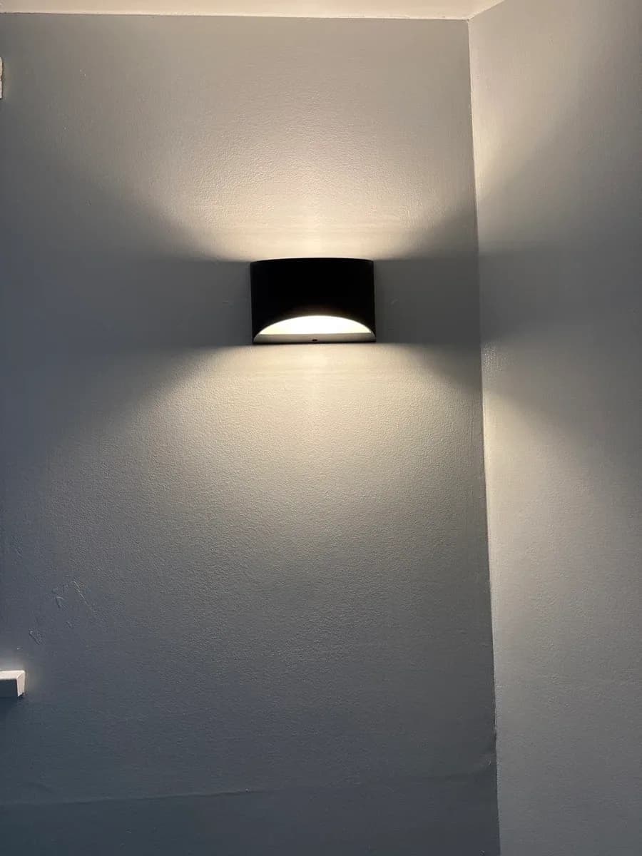 A black wall-mounted light fixture illuminates a gray interior wall.
