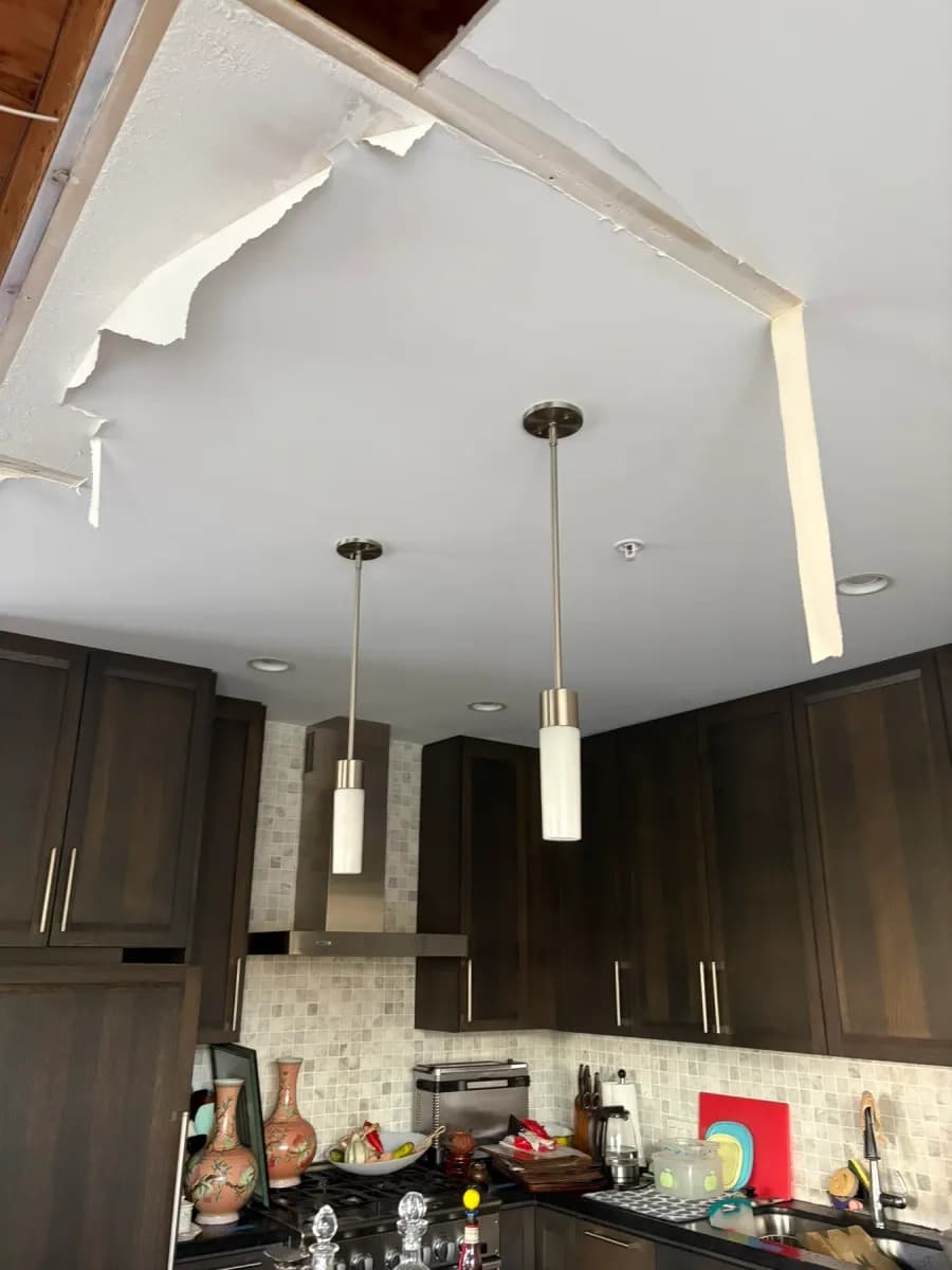 Kitchen ceiling with two hanging pendant lights and several recessed lights above dark cabinetry.