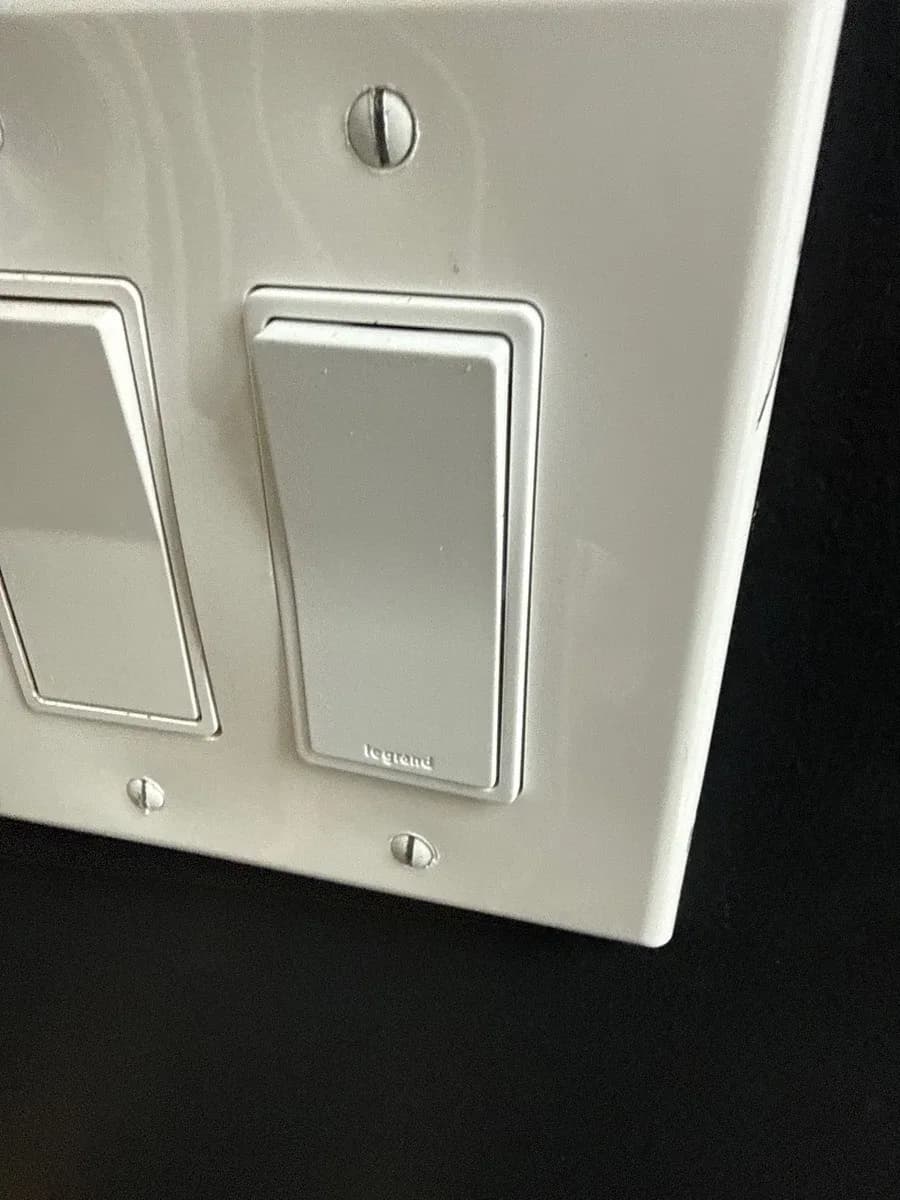 Close-up of a white wall plate with two rocker light switches installed side by side.