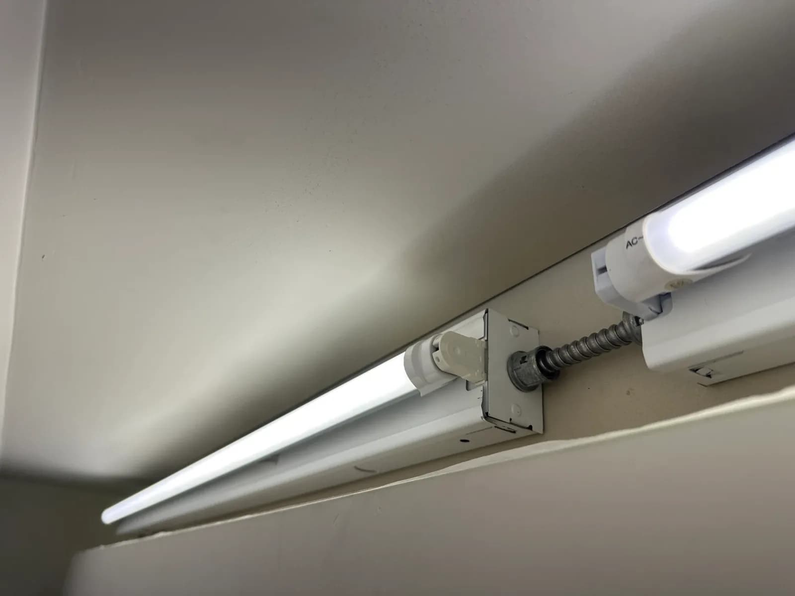Ceiling-mounted fluorescent light fixtures with surface conduit and a junction box.