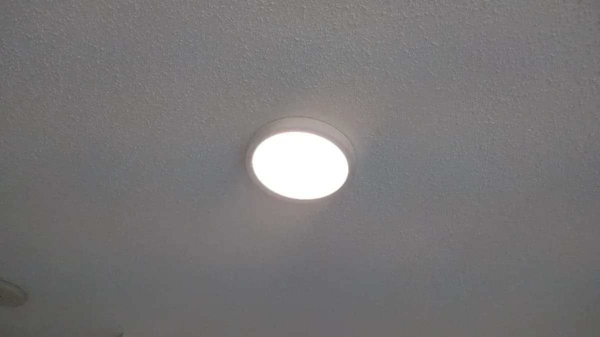 A bright round recessed ceiling light installed in a textured gray ceiling.