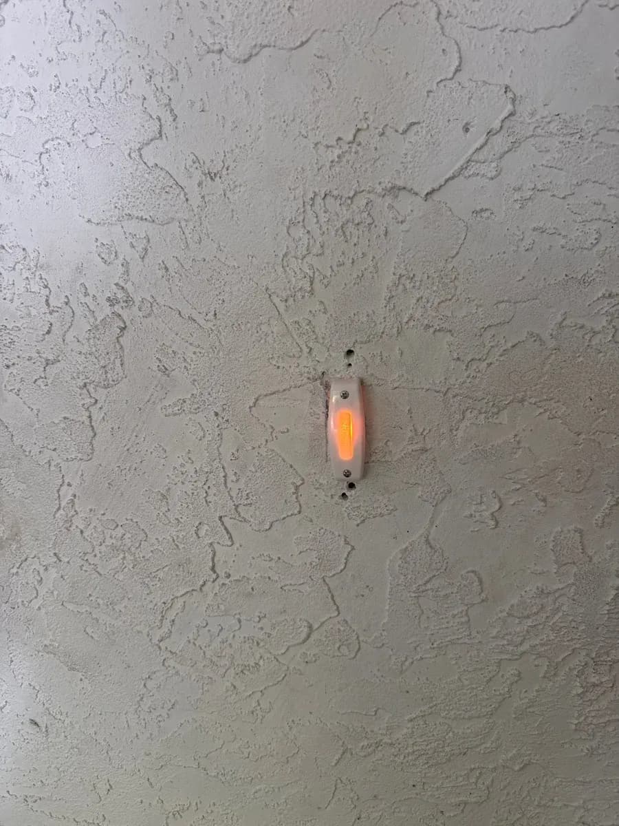 Wall-mounted illuminated electrical device installed on a textured light-colored wall.